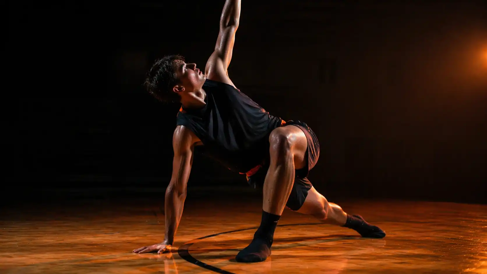 High school basketball player performing dynamic warm-up stretch on indoor court before game