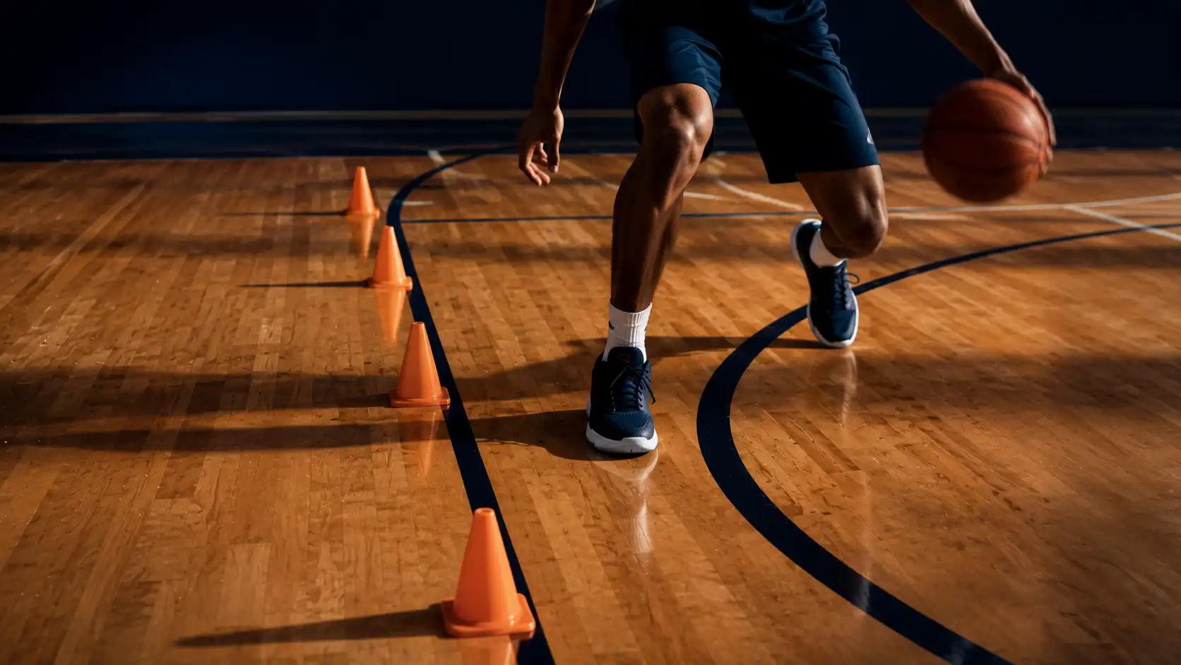 Basketball player working through cone dribbling and footwork drills on a hardwood court