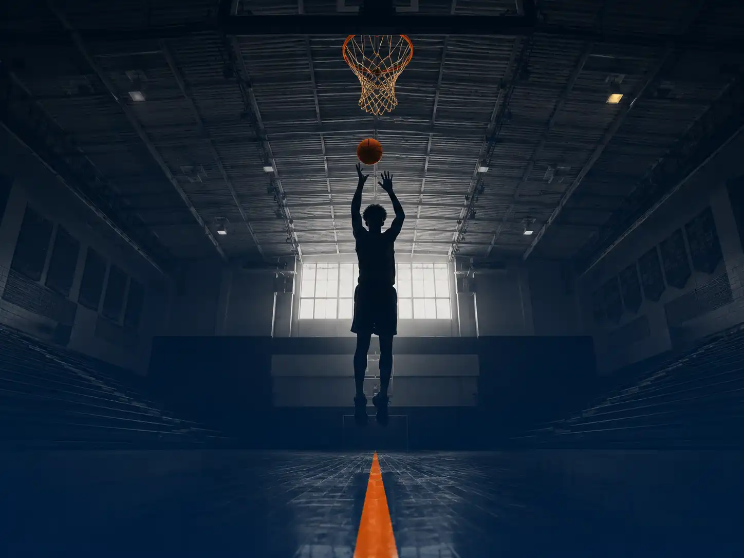 Silhouette of a high school basketball player shooting in an empty gym, symbolizing player development