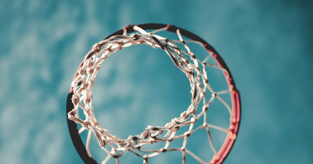 Looking up through a basketball hoop and net against a blue sky