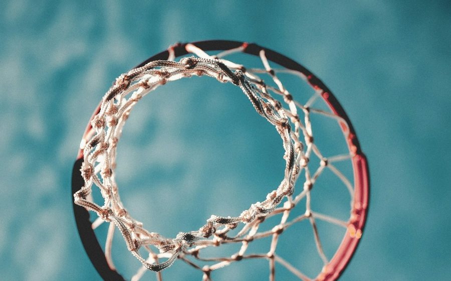 Looking up through a basketball hoop and net against a blue sky